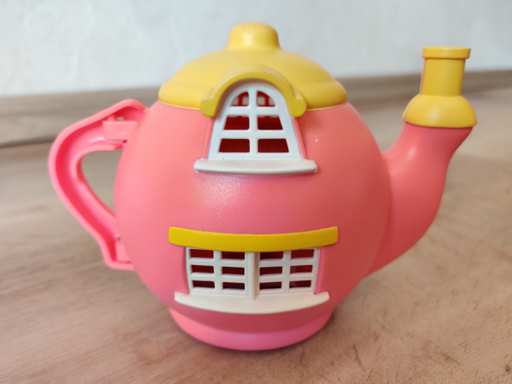 A pink Teeny Weeny Families Hippity Hop Cafe teapot seen from behind.