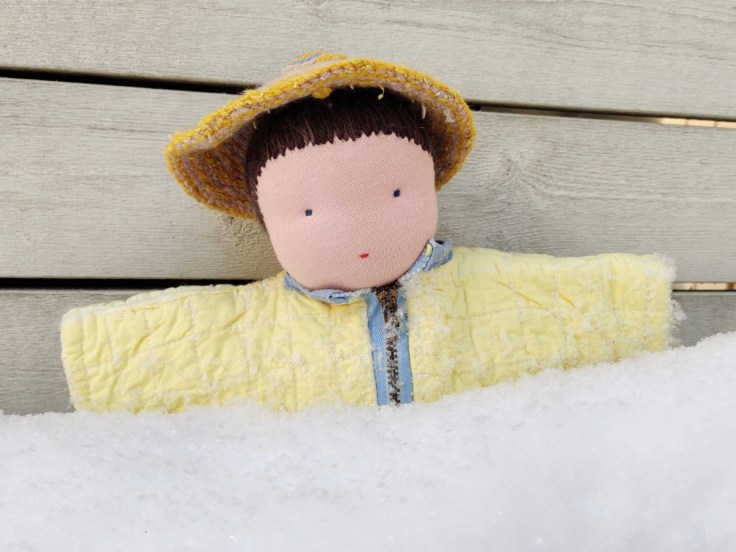 Steiner doll / Waldorf doll out in the snow in a homemade winter coat and crocheted hat.