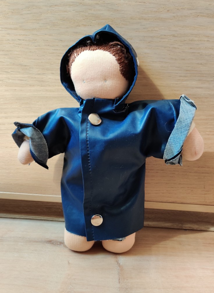A Steiner doll / Waldorf doll in a homemade raincoat.