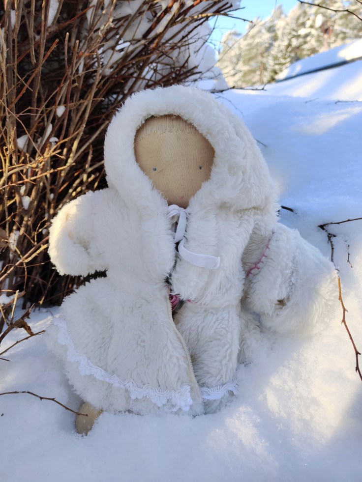 Steiner doll / Waldorf doll out in the snow wearing a homemade white fake fur coat.