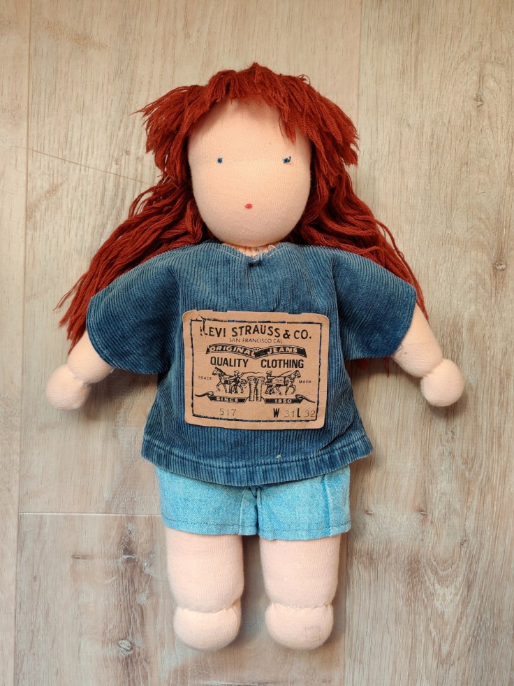 A homemade red-haired Steiner doll / Waldorf doll from 1995 in clothes made from old jeans.